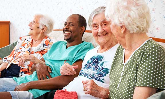 Pfleger mit Bewohner auf Couch lachend